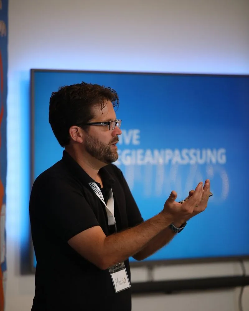 Mario A. Brückner gesturing during a talk in front of a presentation screen